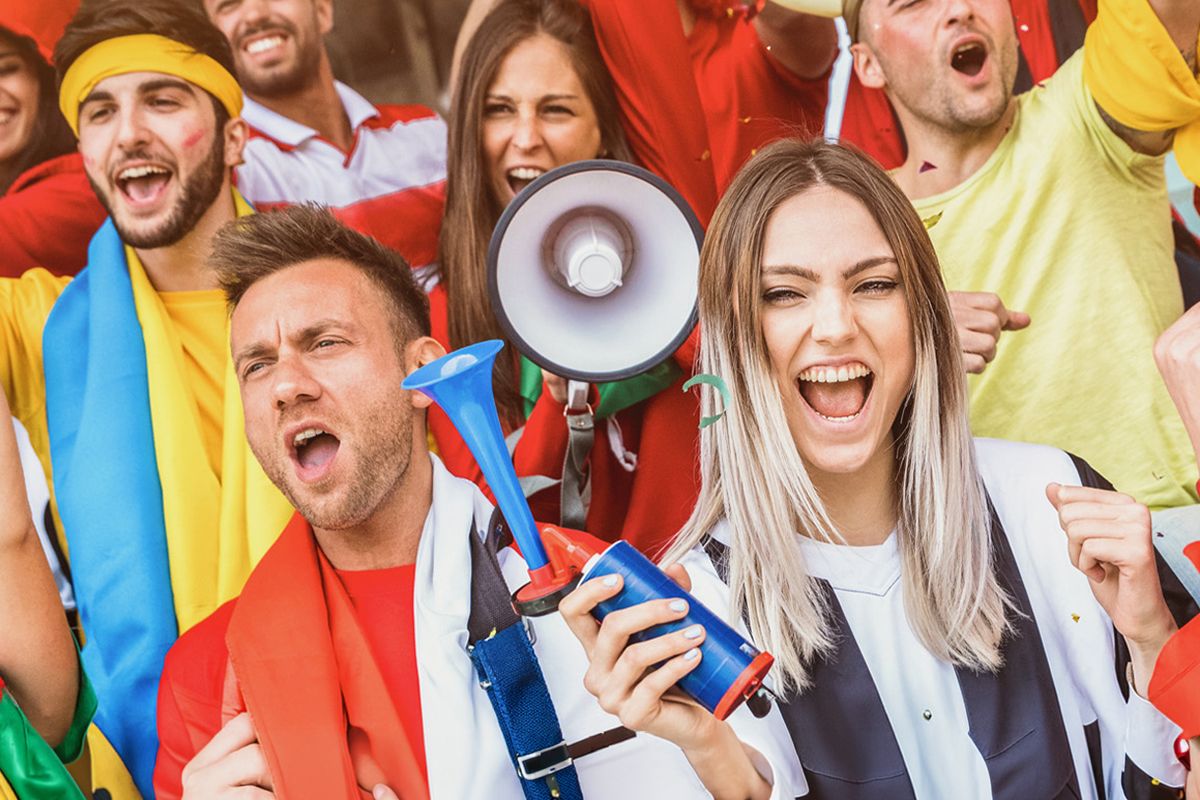 Fußballfans, die jubeln, während sie ein Fußballspiel auf den Tribünen des Stadions verfolgen.
