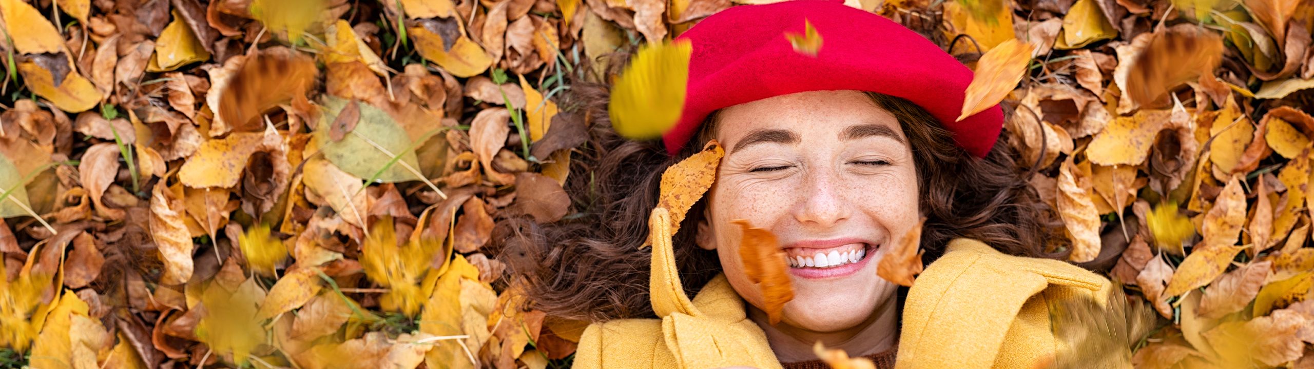 Lachende Frau liegt im Herbstlaub
