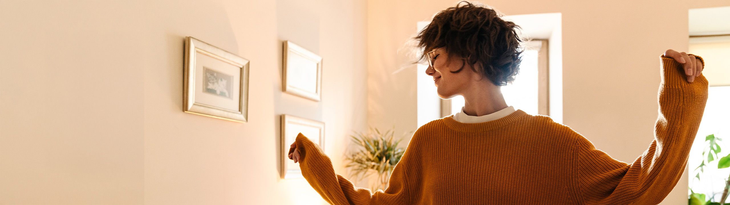 Eine junge Frau tanzt im Wohnzimmer, während sie Musik hört.