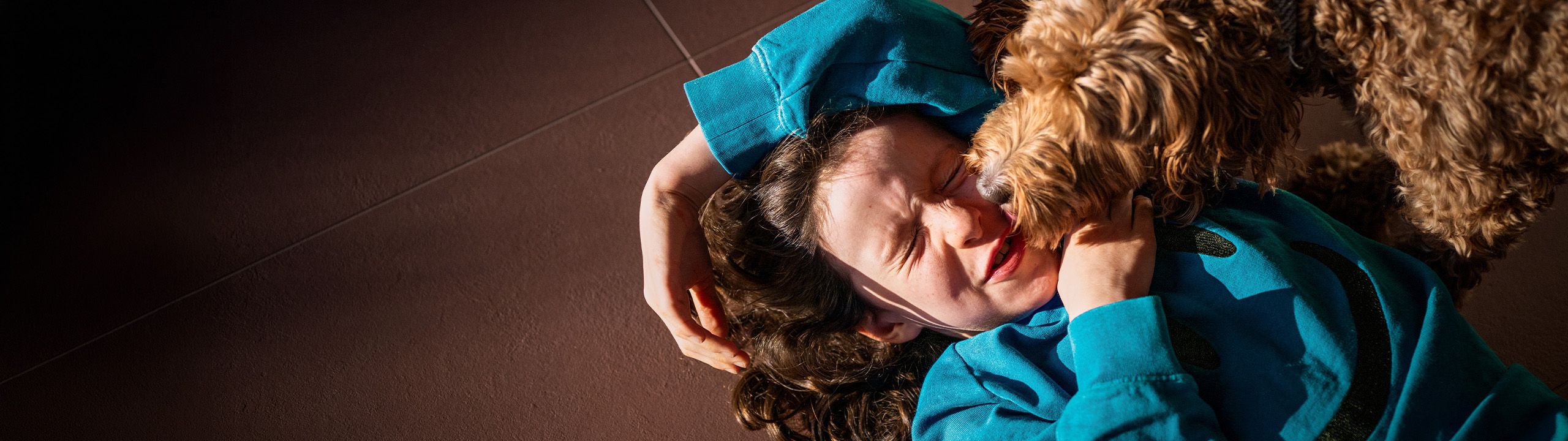 Ein junges Mädchen spielt mit ihrem Hund am Boden.