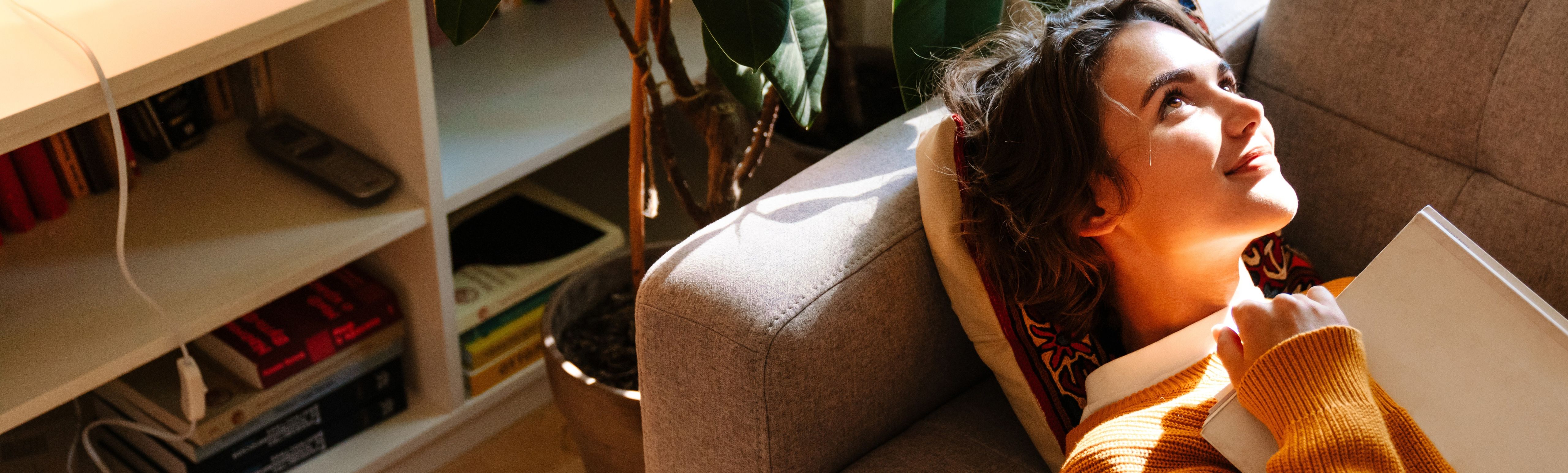 Eine junge Frau, die auf dem Sofa liegt und in die Zukunft blickt.