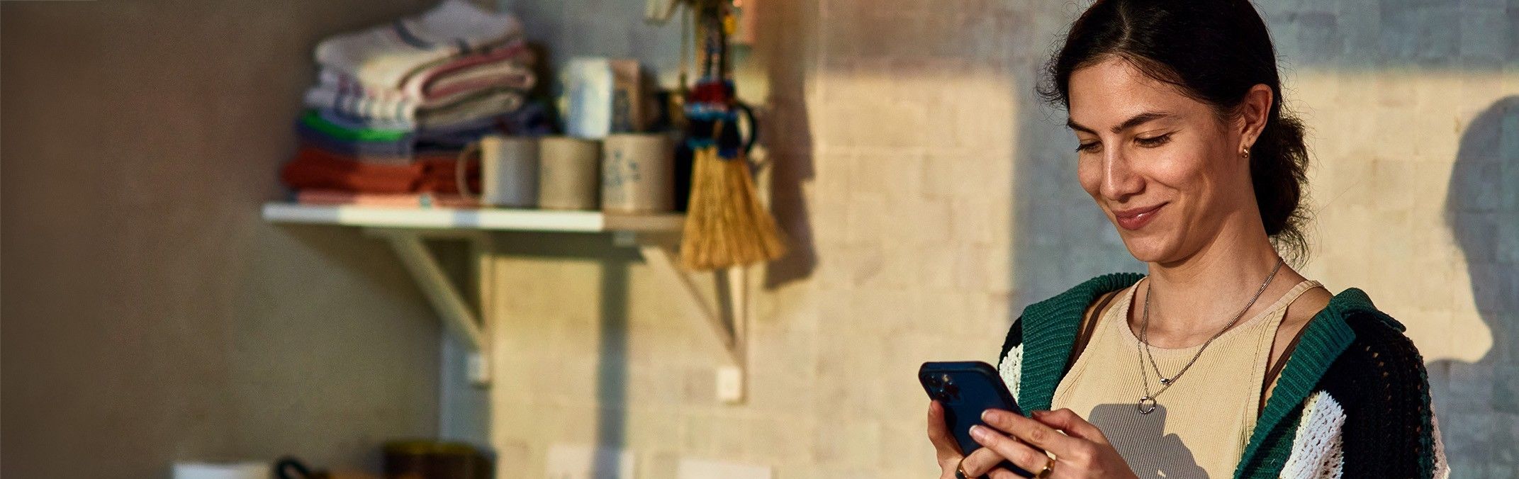 Eine junge Frau blickt auf ihr Smartphone und denkt über einen Online-Kredit nach.