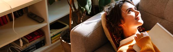 Eine junge Frau, die auf dem Sofa liegt und in die Zukunft blickt.