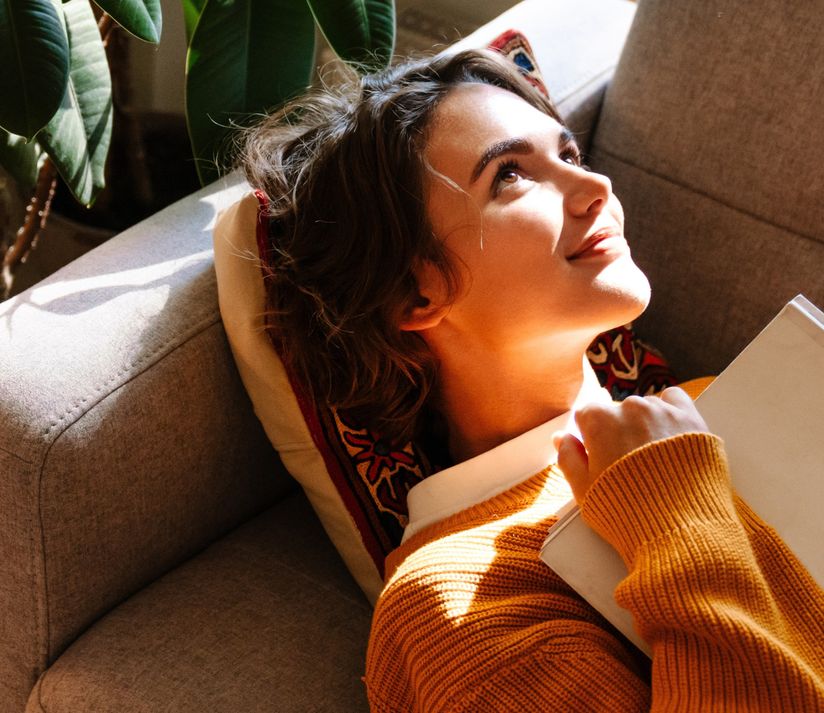 Eine junge Frau, die auf dem Sofa liegt und in die Zukunft blickt.