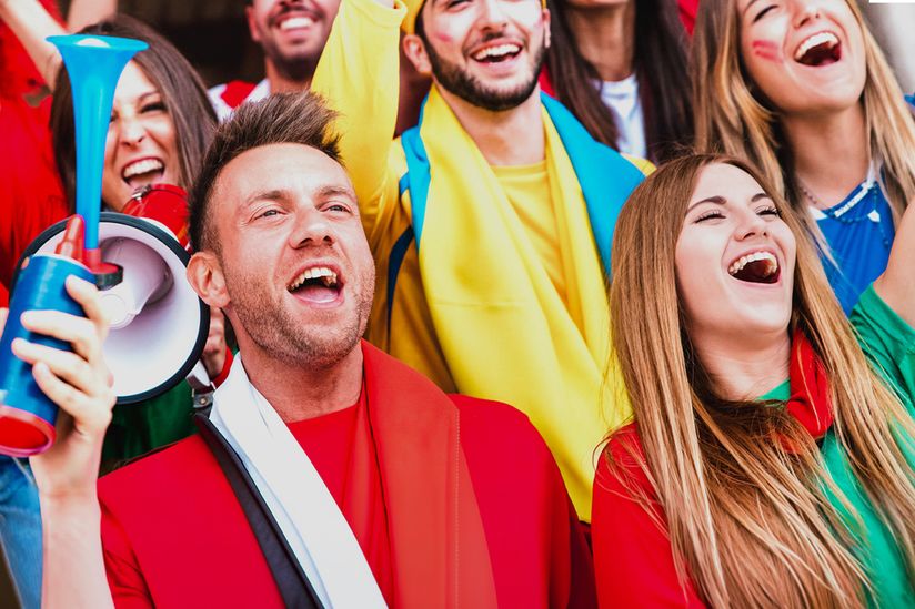 Fußballfans, die jubeln, während sie ein Fußballspiel auf den Tribünen des Stadions verfolgen.